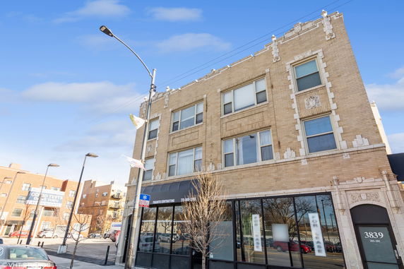 Front view of a multi-story brick building with decorative elements around windows.