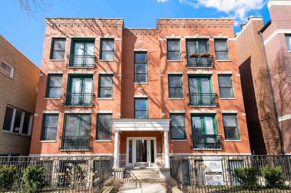 Front view of a brick apartment building with multiple floors and balconies.