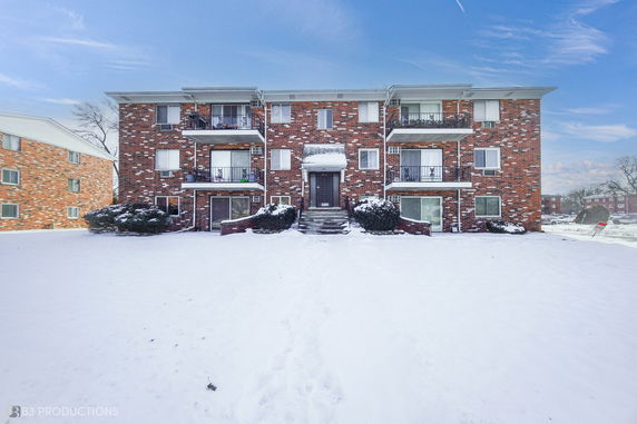Front view of a multi-story brick apartment building with balconies.