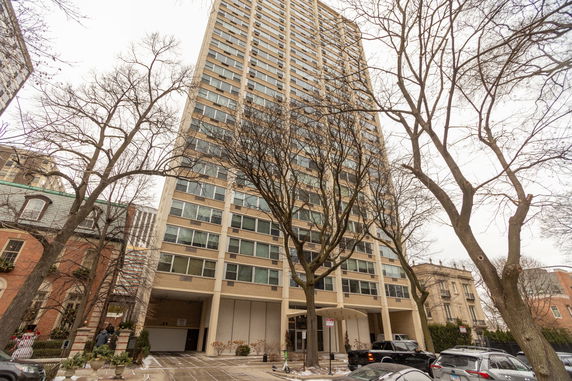 Front view of a tall apartment building with multiple windows and garage entrance.