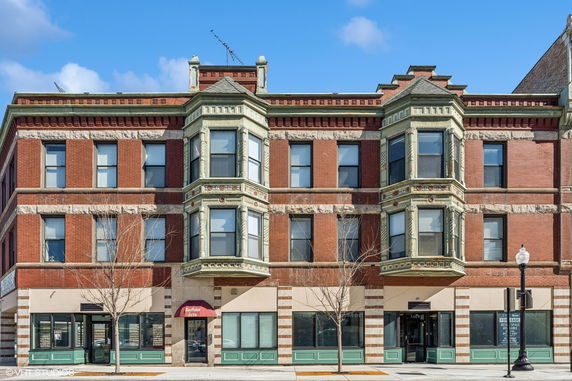 Front view of a multi-story brick building with bay windows and decorative stonework.
