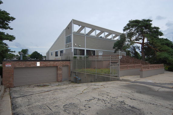 Front view of a modern two-story building with a sloped roof and brick garage.