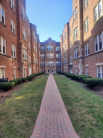 Front view of a multi-story brick apartment building with a central walkway.