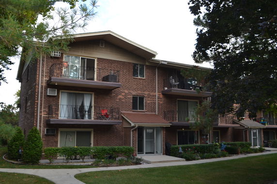 Front view of a three-story brick apartment building with balconies.