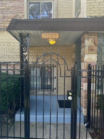 Front view of a house entrance with brick walls and a gated entry.