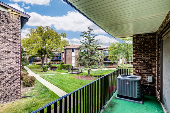 View from a building balcony showing multiple residential structures and landscaped green areas.