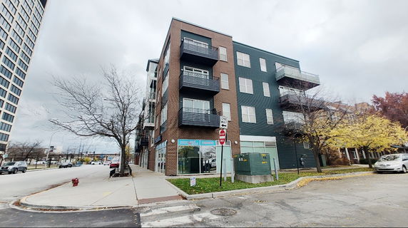 Front view of a multi-story building with balconies and commercial space on the ground floor.