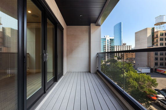 Balcony with glass railing and cityscape view.
