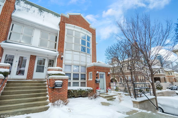 Front view of a multi-story brick house with large windows and a snow-covered entrance.