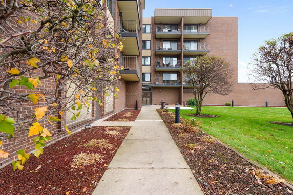 Front view of a multi-story brick residential building with balconies.