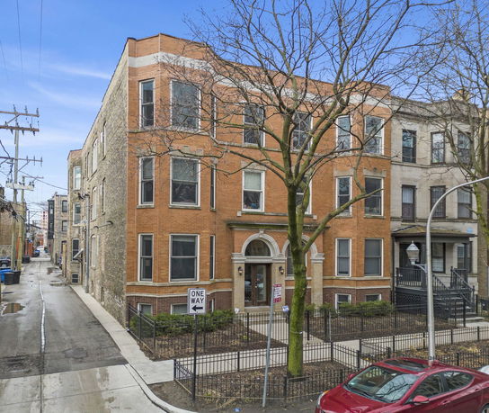 Front view of a three-story brick residential building in an urban setting.