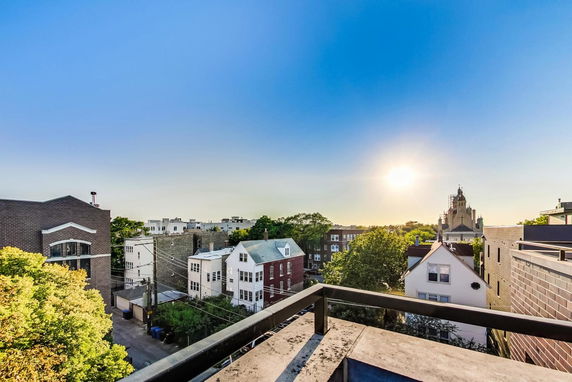 Panoramic view from a rooftop showing various buildings and a clear sky during sunset.
