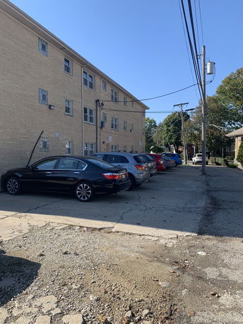 View of an outdoor parking area next to a multi-story building.