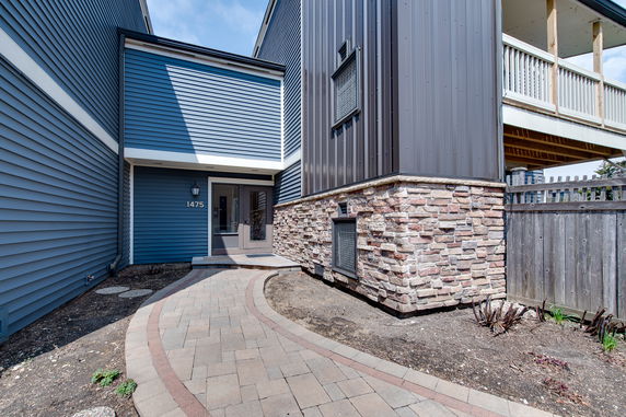 Front view of a modern house with blue siding and a stone accent wall.