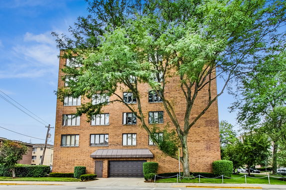 Front view of a multi-story brick building with large windows and an entrance having a garage door.