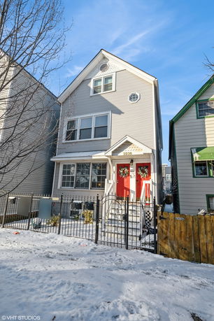 Front view of a three-story house with two red doors and wreaths.