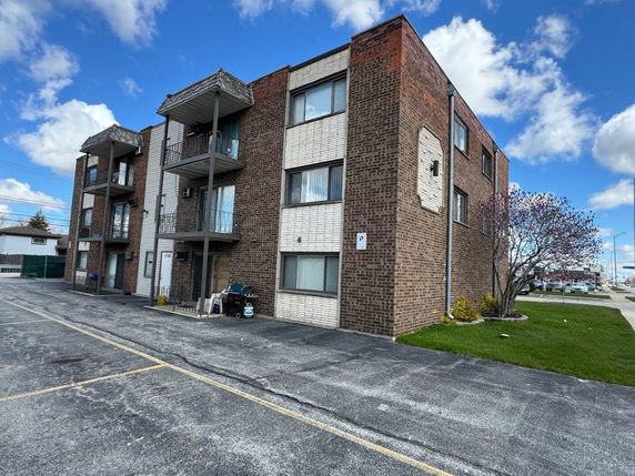 Front view of a three-story apartment building with balconies.