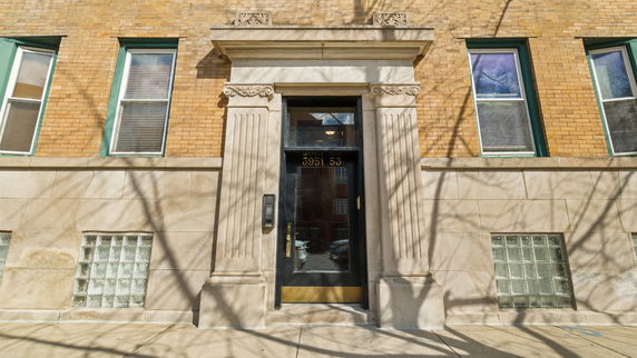 Front view of a building entrance with stone columns and a glass door.