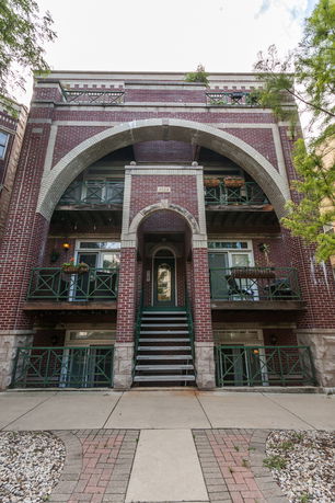 Front view of a multi-story brick building with arched entryway and balconies.