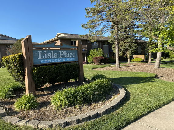 Front view of a condominium complex with a sign reading 'Lisle Place Condominiums'.