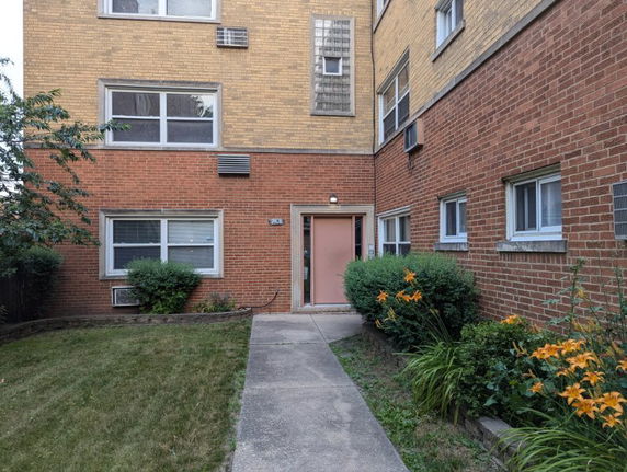 Front view of a brick apartment building with multiple windows and a single entrance.