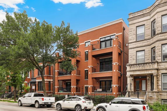 Front view of a multi-story brick residential building with balconies.
