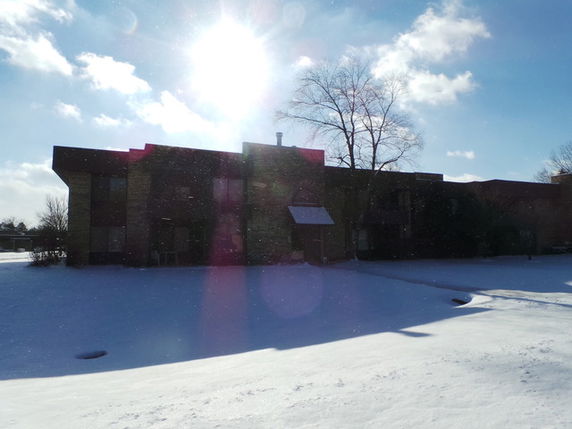 Front view of a two-story house with a flat roof in a snowy landscape.