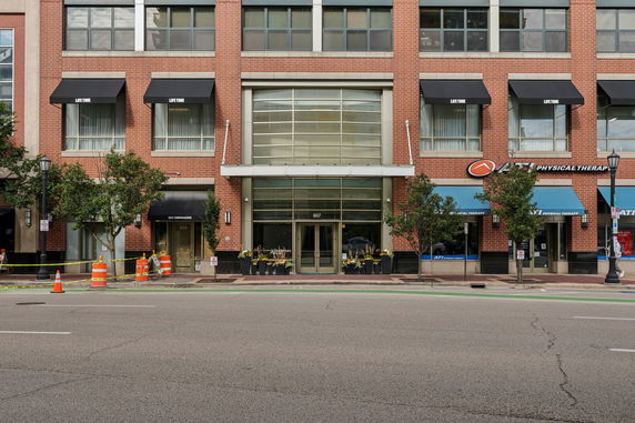 Front elevation of a multi-story building with large glass entrance and brick facade.