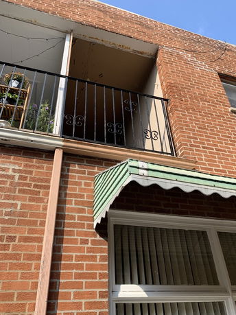 Front view of a brick building with a small balcony and window awning.