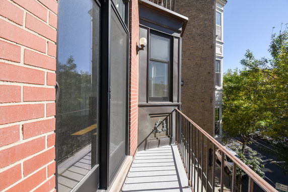View from a narrow balcony overlooking the street with adjacent building.