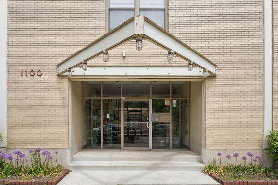 Front view of a brick building entrance with glass doors and a small overhang.