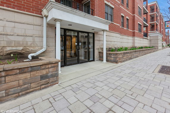 Front view of a brick building with a glass entrance and white columns.
