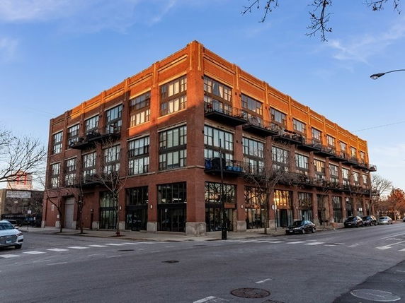 Front view of a multi-story brick building with large windows and balconies.