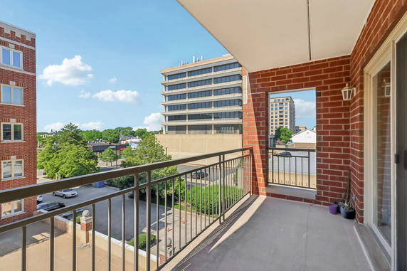View from a balcony looking out at nearby buildings and greenery.