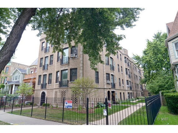 Front view of a multi-story brick apartment building with iron fencing.