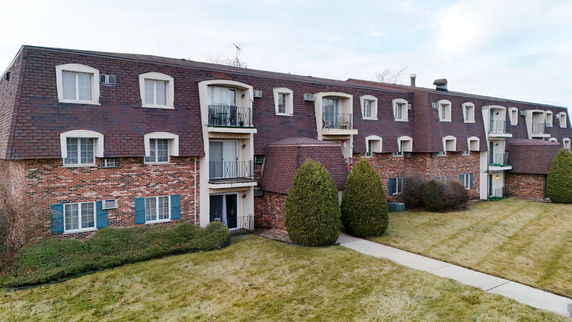 Front view of a multi-story residential building with brick exterior and balconies.