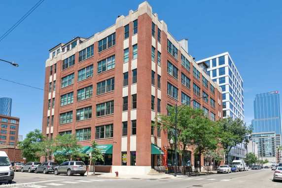 Front view of a multi-story brick building on a city street corner.