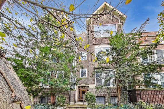Front view of a multi-story brick building with trees in front.