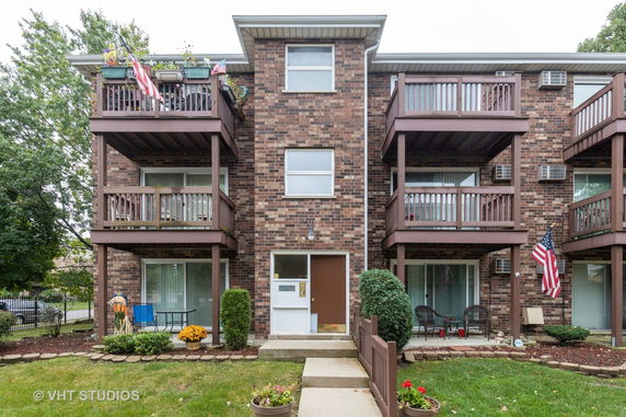 Front view of a three-story brick apartment building with balconies.