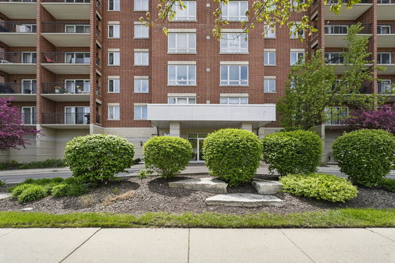 Front view of a multi-story brick apartment building with balconies.
