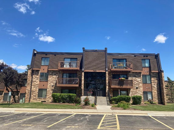 Front view of a three-story apartment building with balconies and brick facade.
