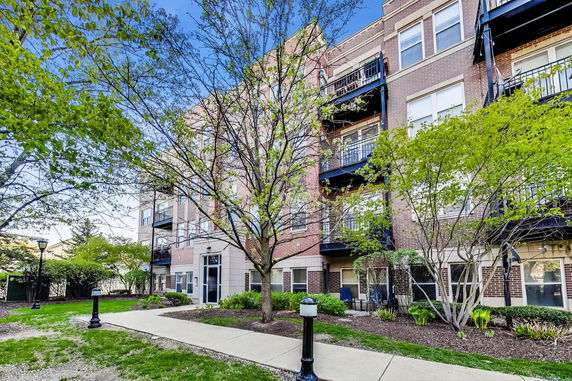 Front view of a multi-story brick apartment building with balconies.