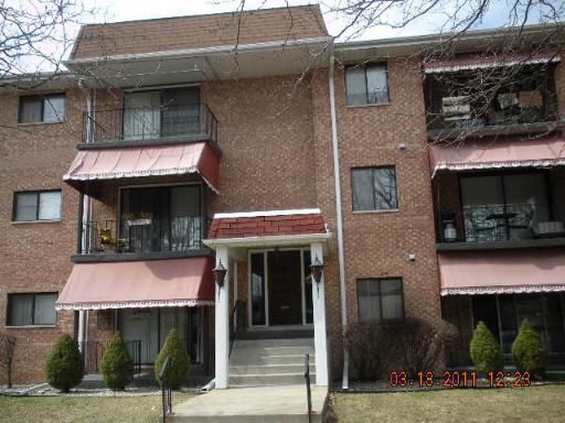 Front view of a three-story brick apartment building with balconies.