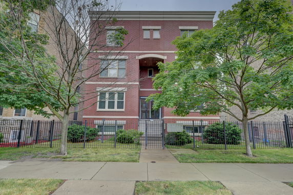 Front view of a multi-story brick building with a gated entrance.
