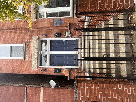 Front view of a brick building with blue double doors and a metal gate.