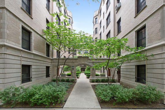 Front view of a multi-story residential building with a courtyard entrance.