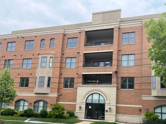 Front view of a multi-story brick apartment building with a central archway entrance.