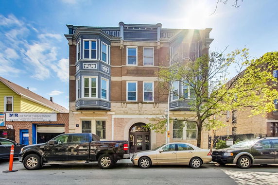 Front view of a three-story residential building with bay windows and brick facade.
