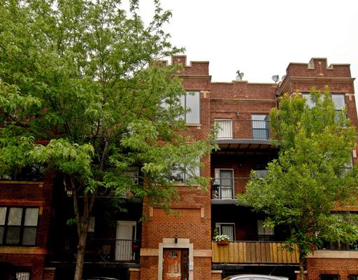 Front view of a multi-story brick apartment building with balconies.