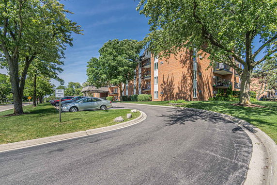 Outdoor parking area in front of a multi-story brick building.